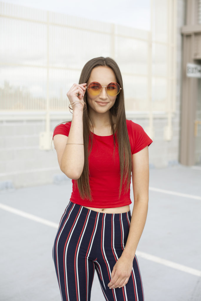 outside portrait of girl holding sunglasses
