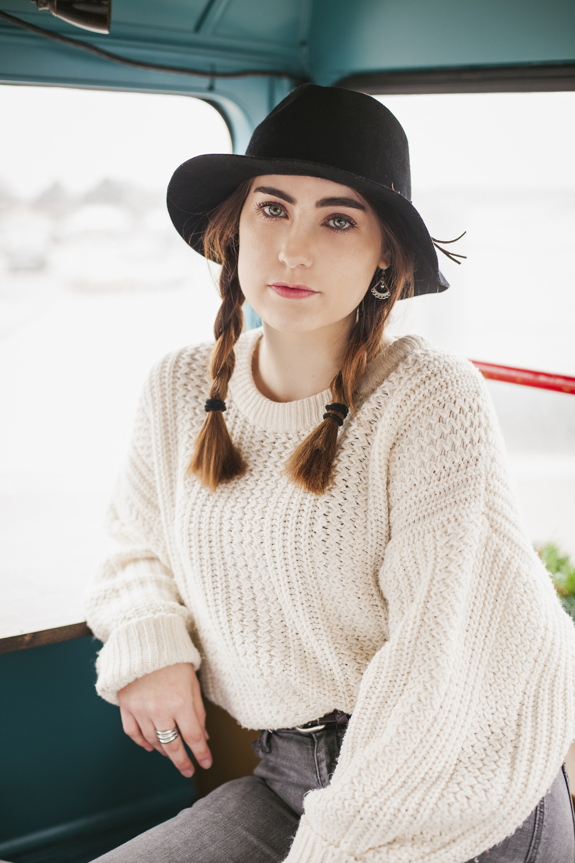 senior picture of girl sitting with a brim hat on and chunky sweater